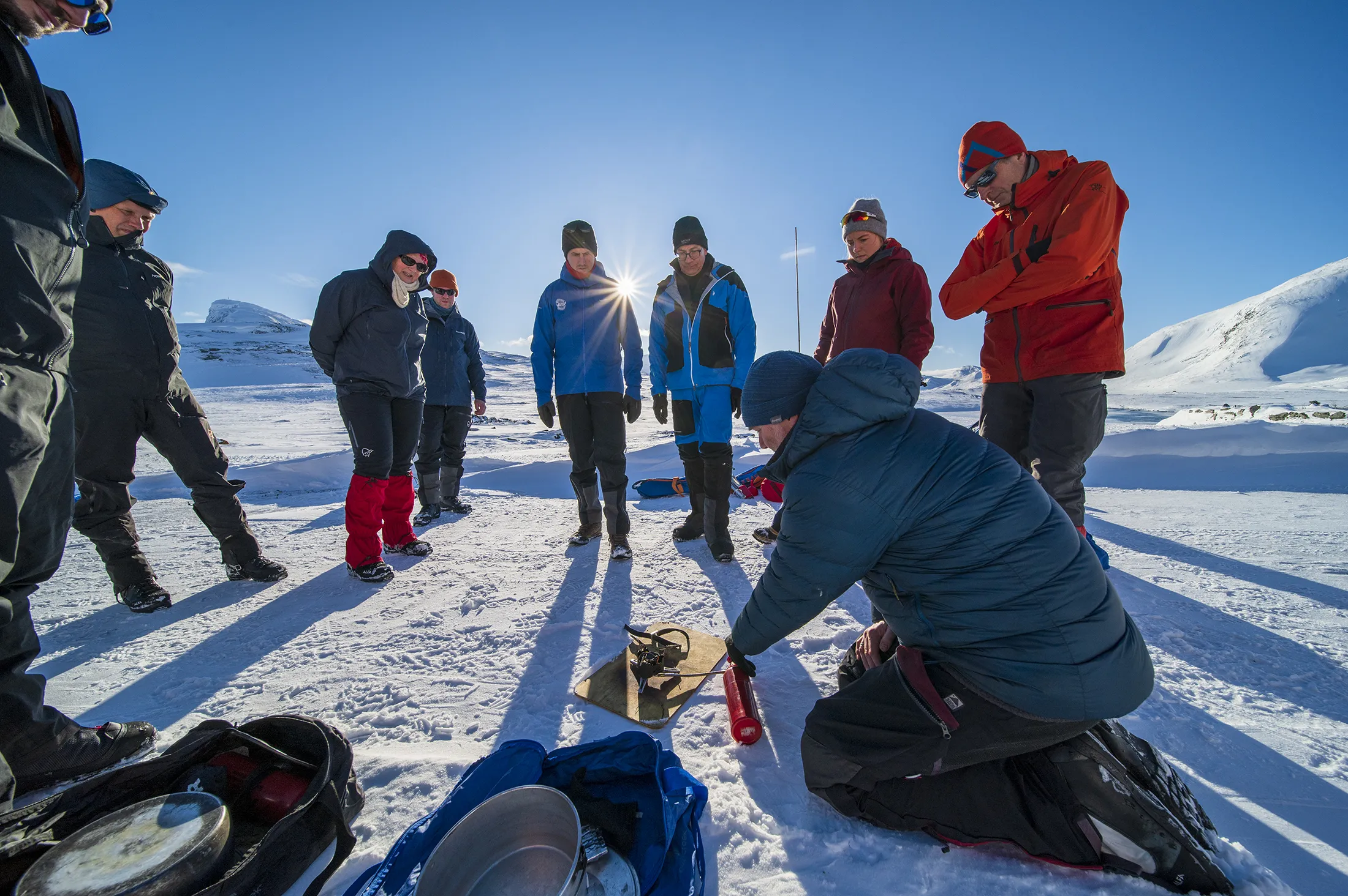 Folk som står ute i snøen og ser på demonstrasjon av en brenner