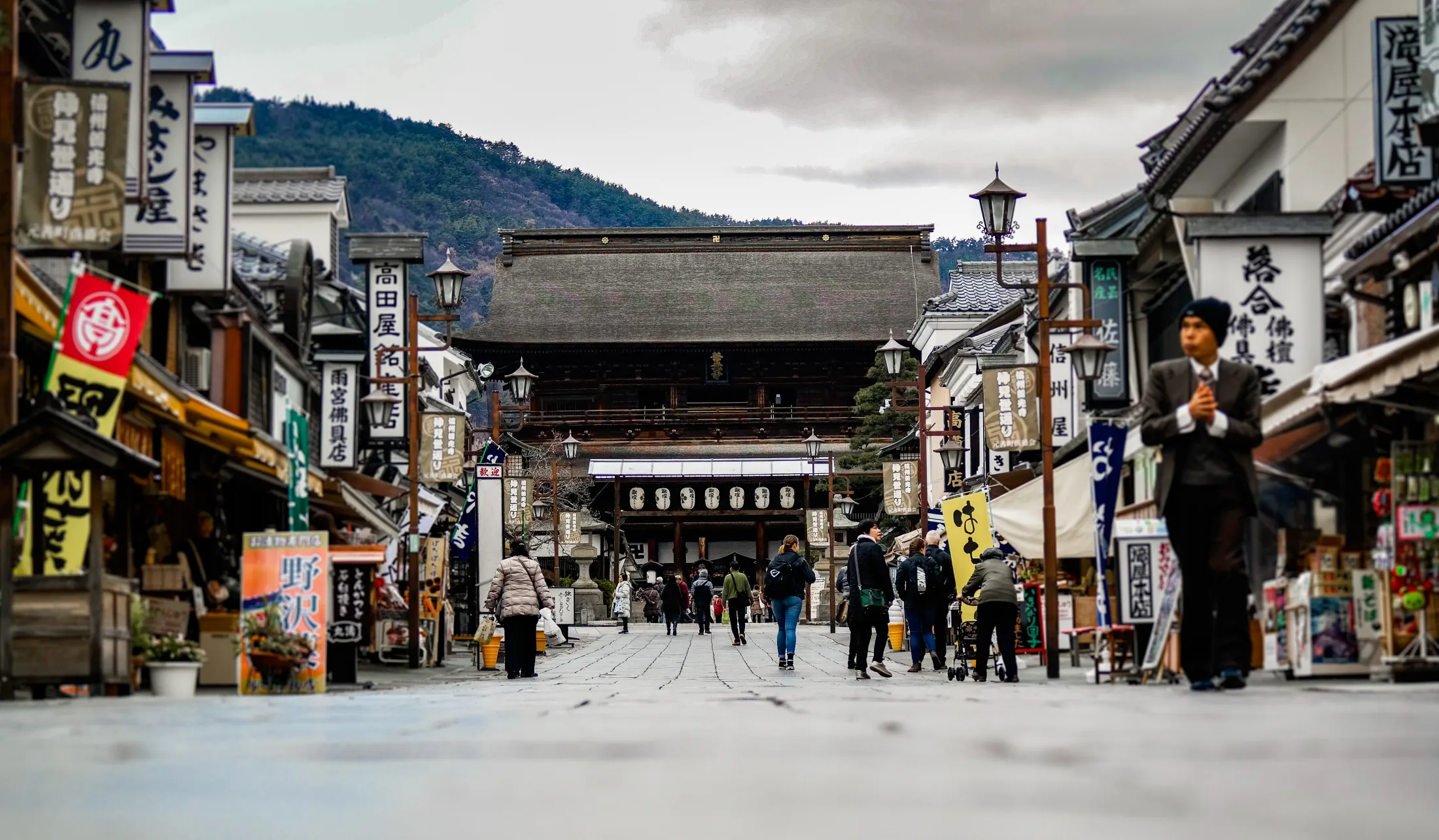 Gate med brostein og tradisjonelle japanske bygninger på hver sin side, og et tempel i enden av gaten.