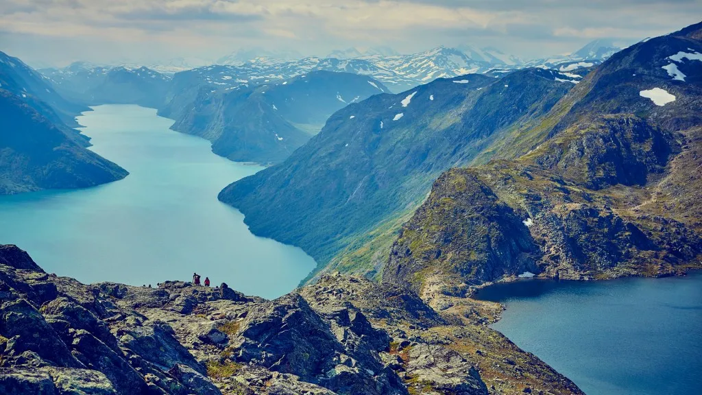 Flott flyfoto av et turkis fjellvann som ligger klemt mellom bratte, kuperte topper i Jotunheimen.