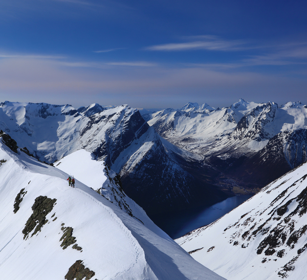 En snødekt fjellrygg som strekker seg over et landskap under en blå himmel.