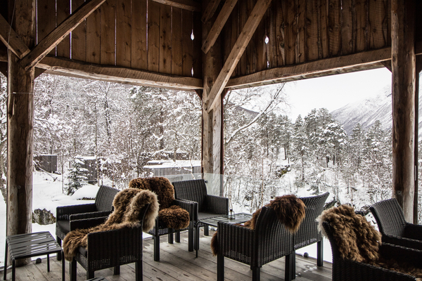 En koselig treveranda med lenestoler og skinnfeller, med utsikt over et snødekt landskap.