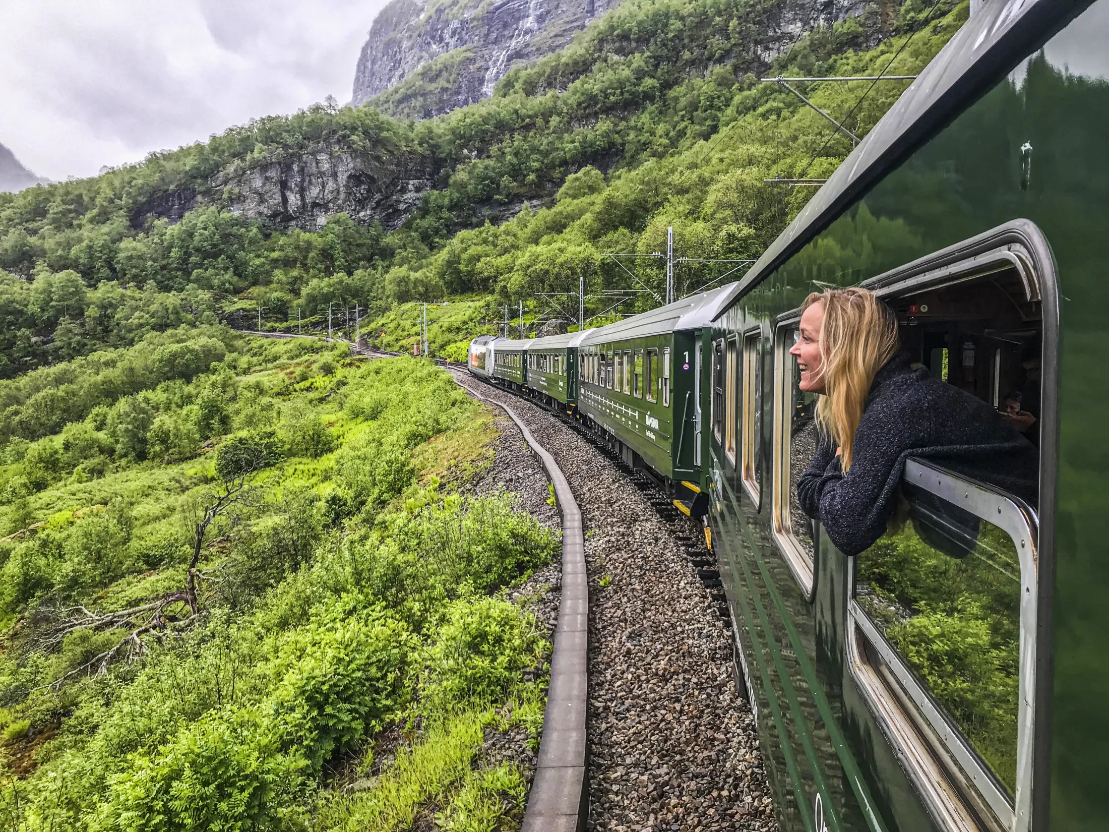 Grønt tog som reiser gjennom et frodig landskap.