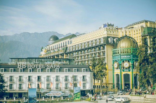 Et vidt bilde av et stort hotell i Sapa i Vietnam, med europeisk-inspirert arkitektur mot en bakgrunn av fjell.