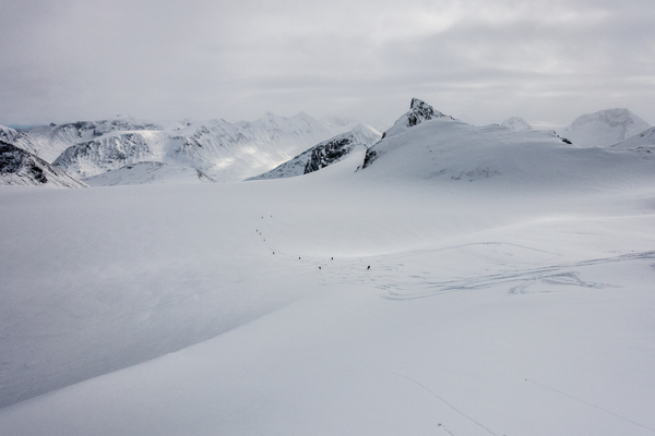 Et snødekt landskap med majestetiske fjell under en overskyet himmel.
