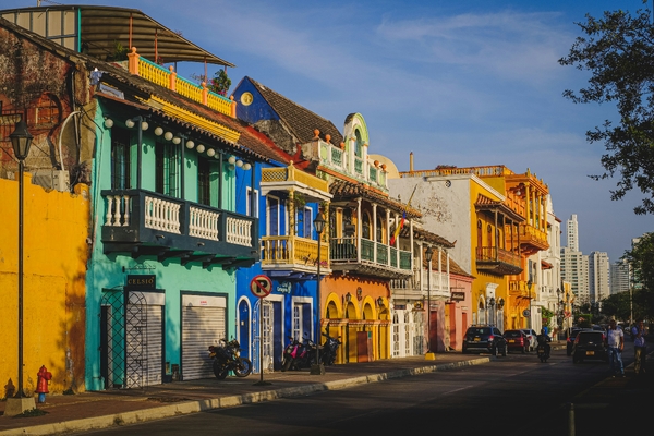 En gate i Cartagena i Colombia, kantet med sterkt fargede kolonibygninger og balkonger under en klar blå himmel.