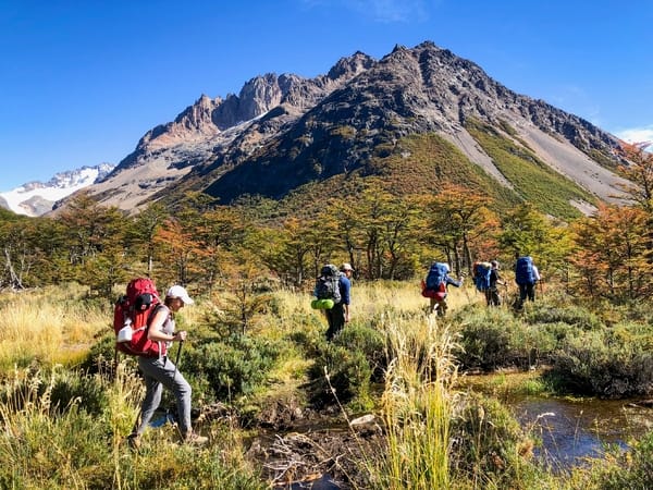 Turgåere som går gjennom et landskap med et stort fjell i bakgrunnen.