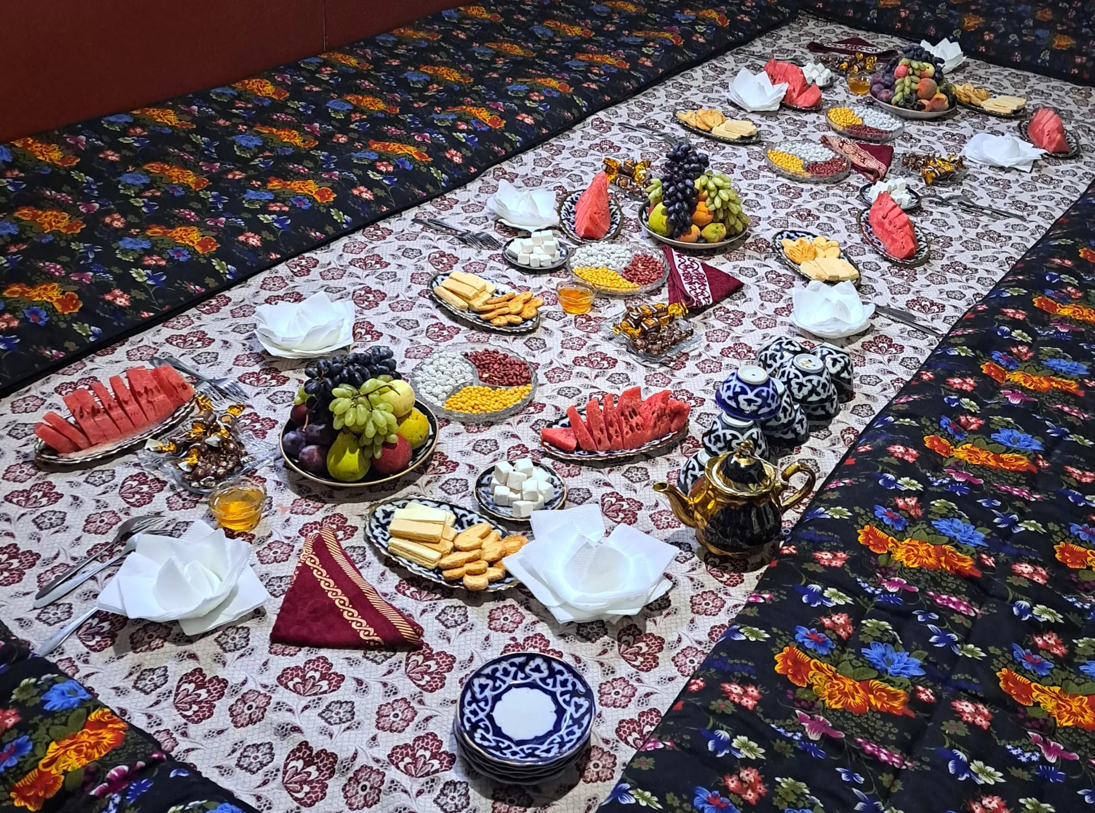 Et lavt bord er vakkert dekket med mønstrede duker, puter og en rekke retter med vannmelonskiver, frisk frukt, nøtter, kjeks og tradisjonelle tesett.