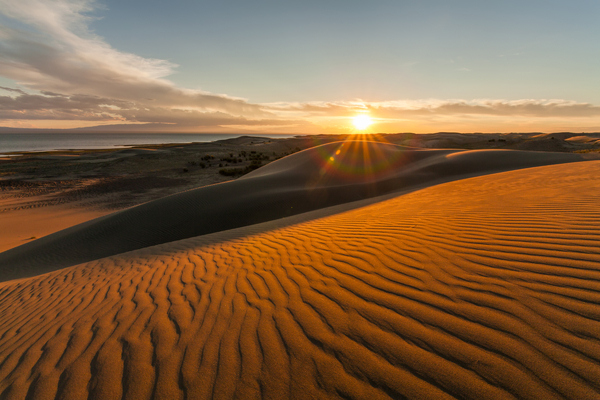 Solnedgang bak sanddyner i ørkenen