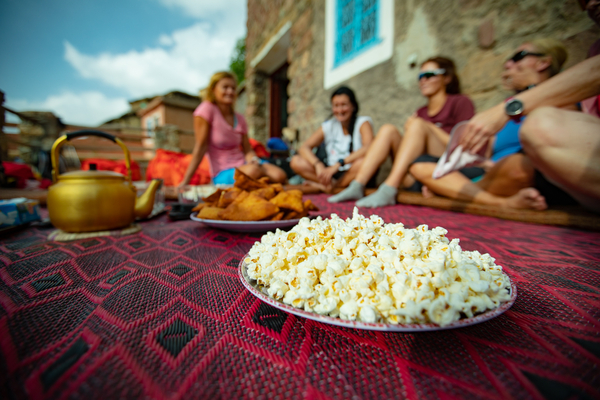 Folk på et teppe utenfor en bygning som spiser snacks og popcorn