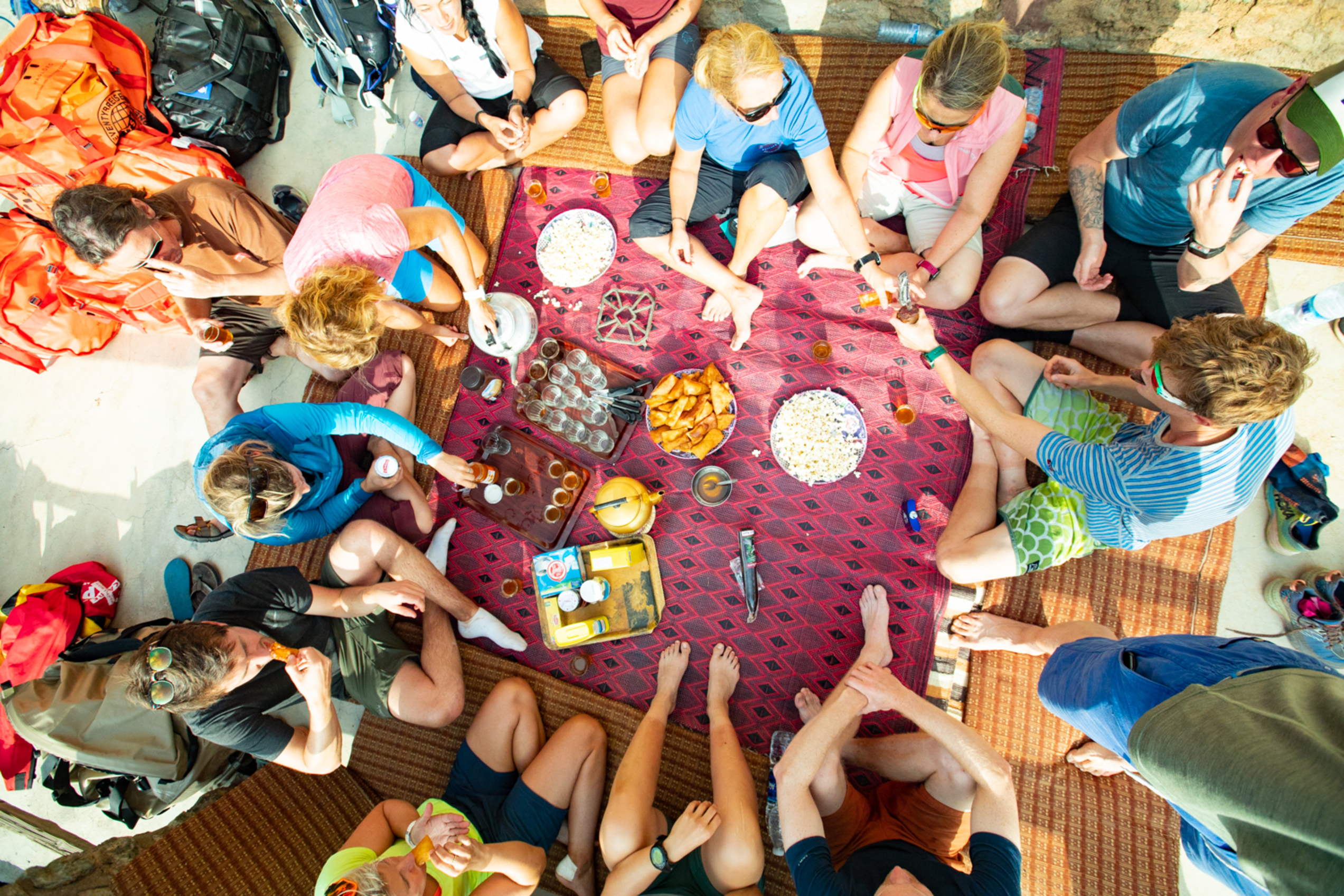 En gruppe mennesker sitter på bakken og drikker te og spiser snacks