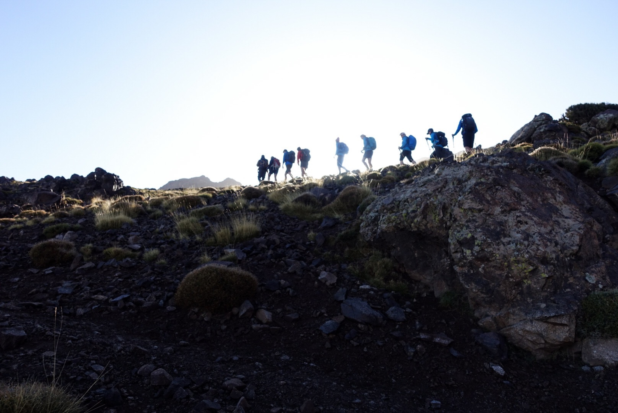Folk som går på en rygg i fjellet med blå himmel