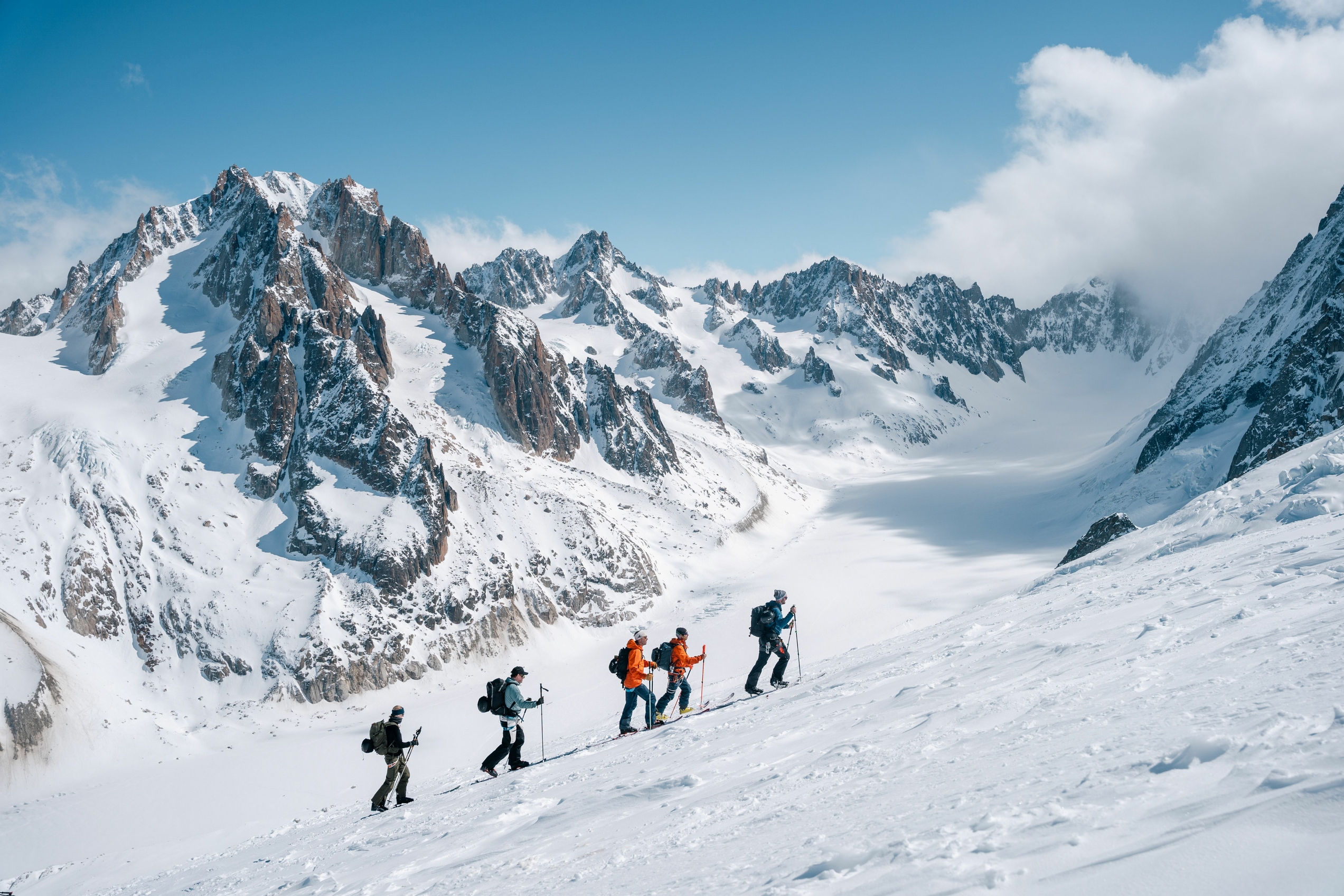 Gruppe på ski på topptur ved en isbre og blå himmel