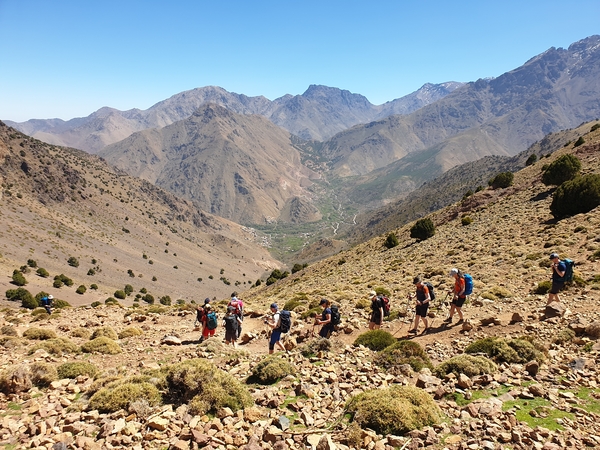 Folk som går nedover en sti inn i en dal i et tørt fjellområde