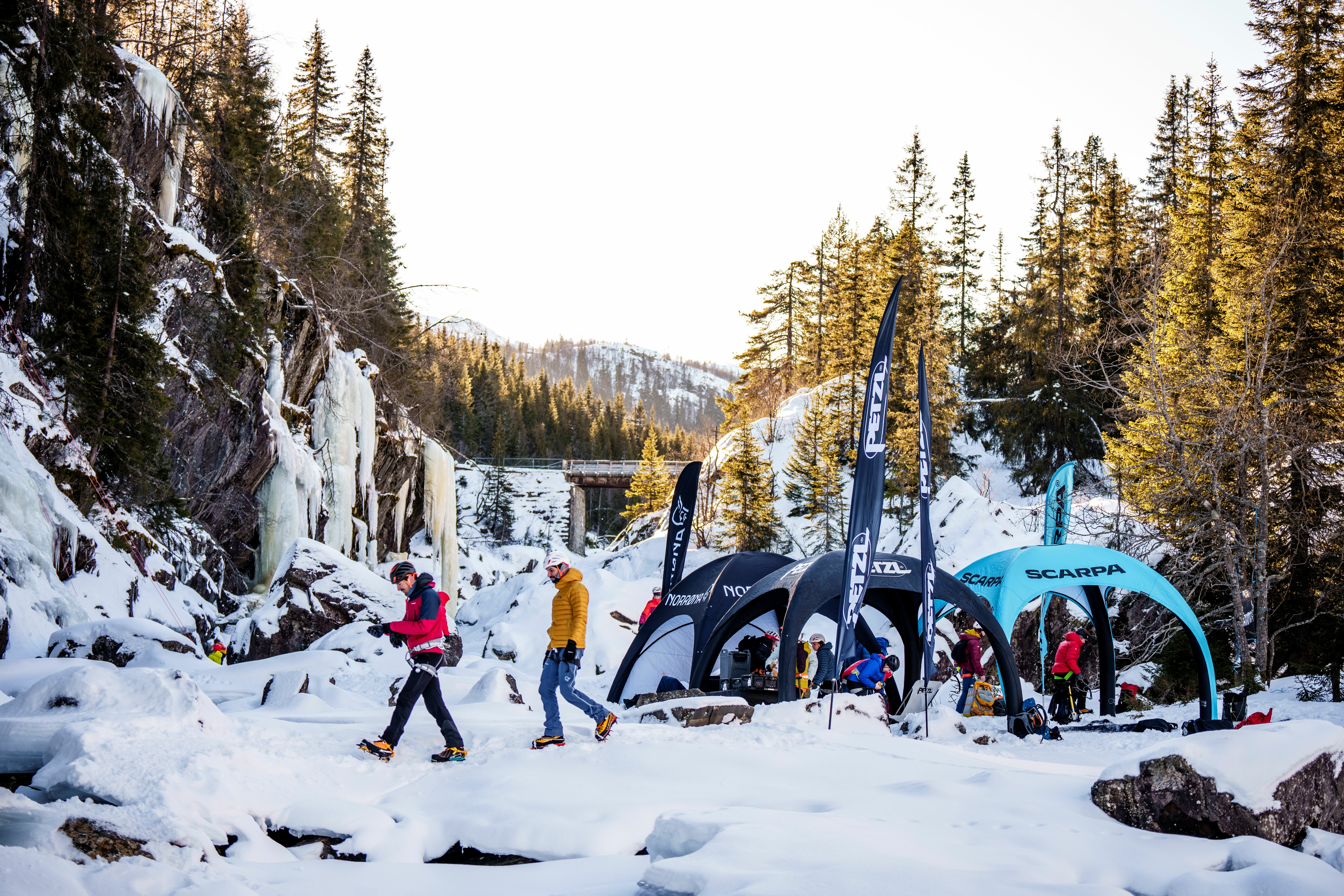 Mennesker i et snødekt områder rundt en elv med telt