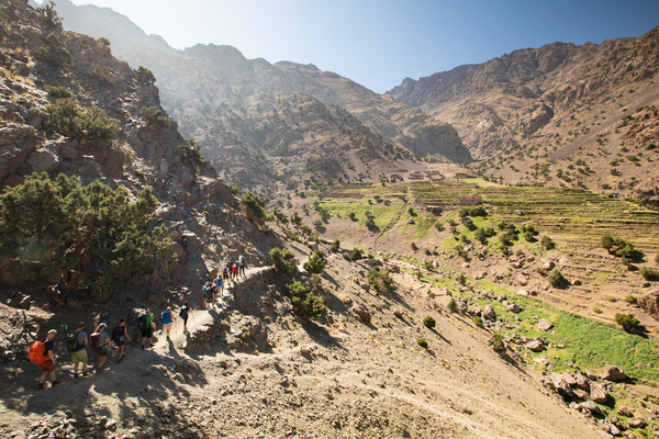 Turgåere i en tørr dal i fjellene med grønne trær