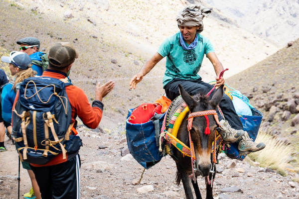 En fyr som rir på et muldyr som passerer turgåere