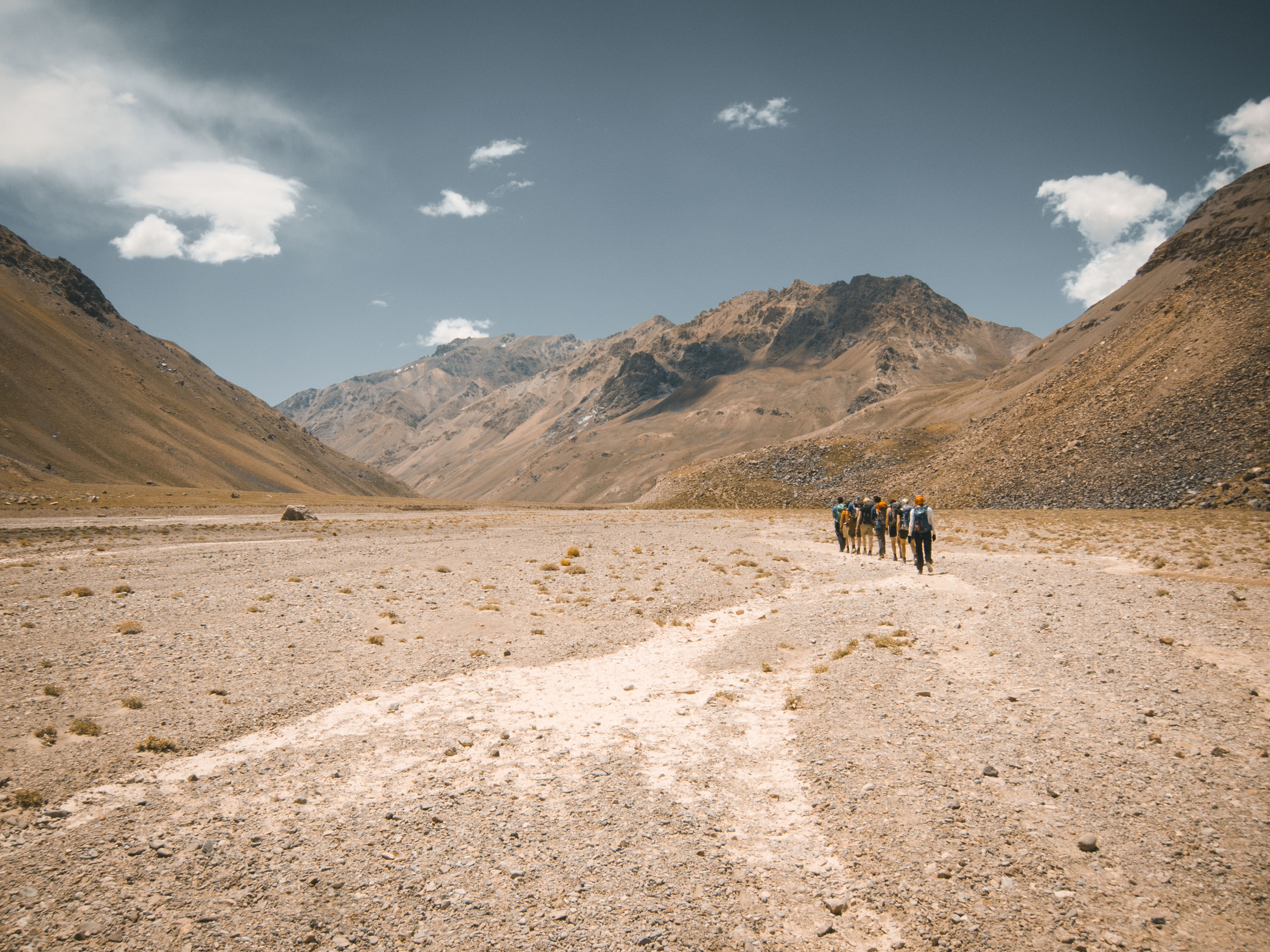 Gruppe mennesker gående gjennom uttørket elveleie i dal