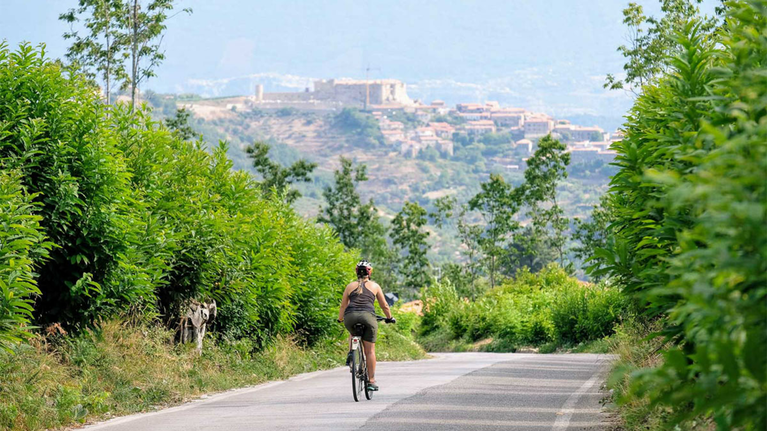 Sykkeltur på vei med vakker by i bakgrunnen