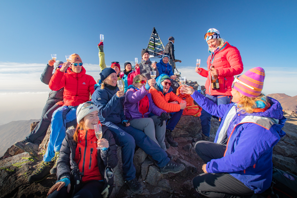 Turgåere feirer på toppen av et fjell med champagne